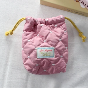 Detailed view of pink quilted fabric camera pouch with yellow drawstring and heart pattern