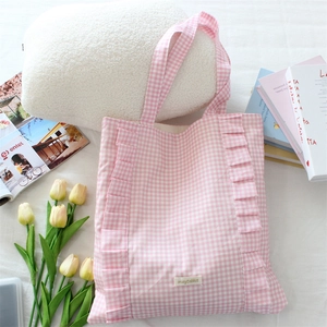 Gros plan du sac fourre-tout à carreaux roses et blancs avec volants et étiquette de marque