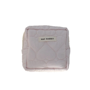 Quilted pink makeup pouch with heart pattern and brand label on white background