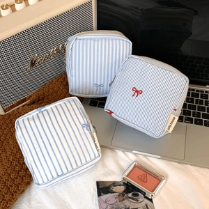 Detail of striped canvas pouch with bow embroidery and metal zipper closure