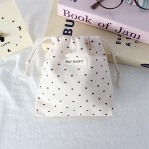 Close-up of a small polka dot drawstring pouch with heart patterns and woven label