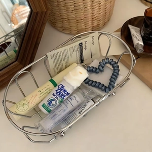 Overhead macro view of a silver wire basket holding skincare items on a wooden table