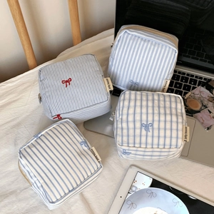 Close-up of blue striped fabric storage bags with small bow embroidery and brand label