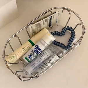 Detail of oval stainless steel wire basket holding toiletries for desktop organization
