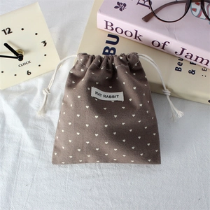 Detailed view of the brown drawstring bag with heart prints and a stitched fabric label