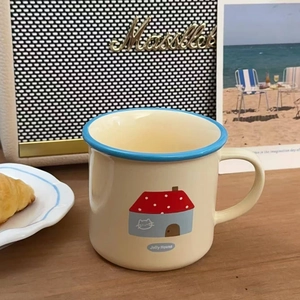 Close-up of vintage ceramic mug with Jolly House cartoon house print on a desktop
