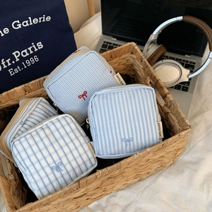 Set of four striped fabric pouches in a wicker basket with cute bow embroidery detail