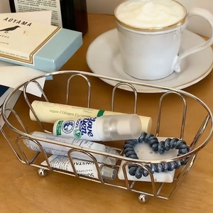 Macro shot of silver oval iron wire basket with skincare products on wooden desk