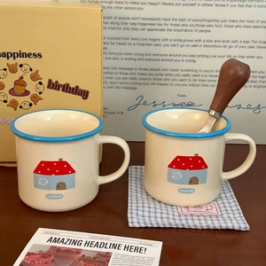 Close-up of ceramic mugs with cat pattern, blue rim, and wooden stirring spoon