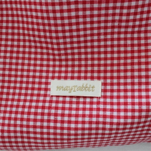 Détail du tissu à carreaux vichy rouge avec étiquette cousue et broderie dorée