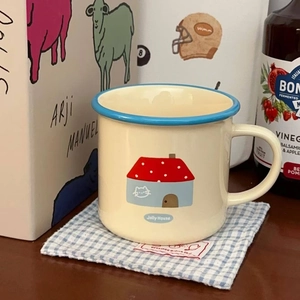 Close-up of a cute ceramic mug with house illustration on a blue checkered tablecloth