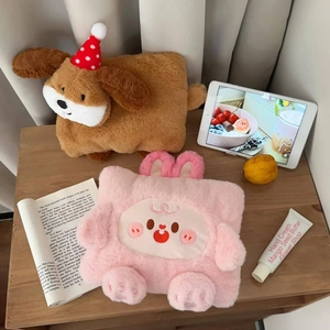 Detail of plush cartoon hot water bottle covers in puppy and rabbit designs on a desk