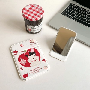 Macro view of portable cartoon bear makeup mirror and Magsafe card holder on a desk