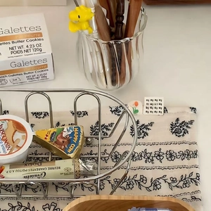 Close-up of a silver mesh iron storage basket on a table with snacks and cookies