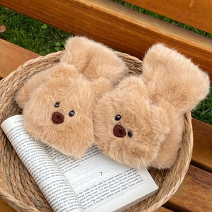 Detail of soft brown plush bear mittens in a cozy basket on an outdoor wooden bench