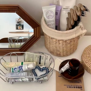 Close-up of a silver wire storage basket with sphere feet and a woven basket on a vanity
