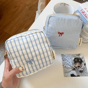 Detail of canvas pouches with bow embroidery and metal zipper for daily storage