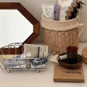 Close-up of a silver oval hollow iron basket with spherical feet for bathroom storage