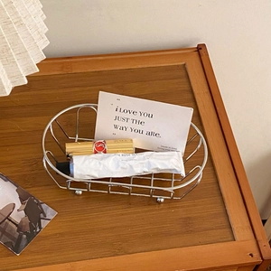 Top-down view of a minimalist silver iron wire storage basket on a dark wooden desk