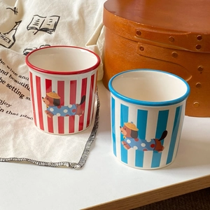 Close-up of red and blue striped ceramic mugs featuring cute cartoon dachshund dog patterns