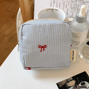 Detail of blue striped tofu-style pouch with red bow and metallic zipper closure