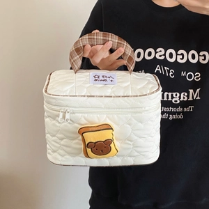 Dettaglio della borsa da toilette trapuntata bianca con manico a quadri e orsetto