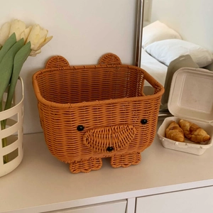 Detailed view of bear-shaped orange woven storage basket on a white desktop setting