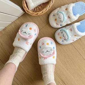Pantoufles chat en peluche mignonnes en rose et bleu sur parquet en bois