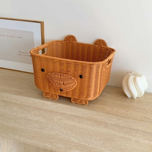 Detail view of the hand-woven orange bear storage basket with cute ears and sturdy handles