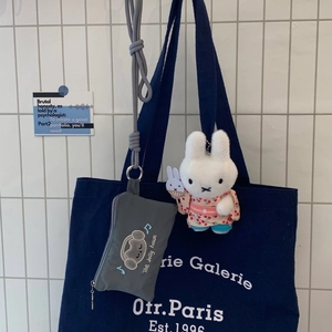 Detail of grey cat embroidered card pouch with Miffy plush keychain and canvas tote bag