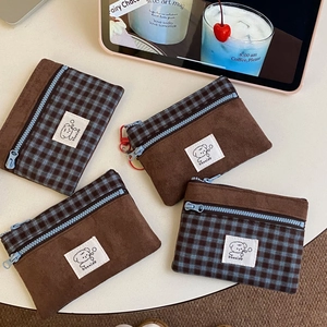 Detail of suede and plaid patchwork coin purse with blue zipper and cute bear label