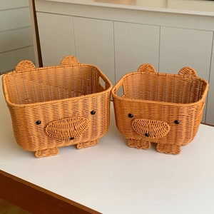 Set of two bear-shaped woven storage baskets in light brown on a white desk surface