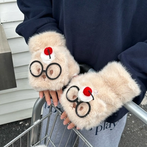 Détail de mitaines en peluche beige avec lunettes de dessin animé et pompon rouge sur caddie