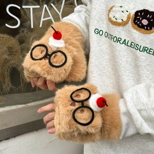Détail de gants pelucheux avec cerise 3D et lunettes sur une fausse fourrure beige