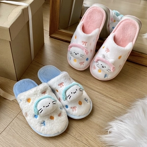 Détail de chaussons chat en peluche avec casque 3D et broderie de nœuds colorés