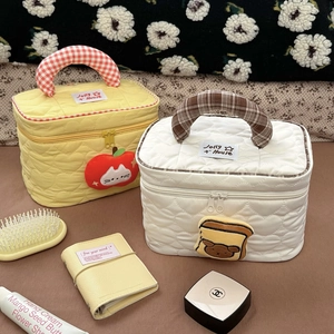 Dettaglio di pochette trapuntate a cuore con manico a quadri e ricami cartoon
