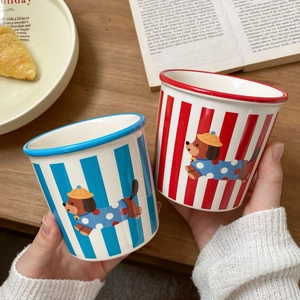 Close-up of striped ceramic mugs with cartoon puppy patterns on a wooden tabletop
