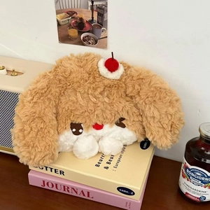 Close-up of plush teddy dog hot water bottle with cherry detail on decorative books