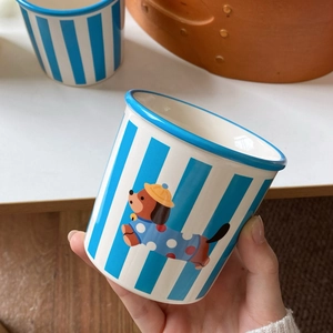 Detail of hand-held ceramic striped mug featuring a cute cartoon dachshund illustration