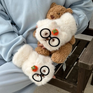 Détail de gants en peluche avec breloque orange et lunettes sur une fourrure synthétique