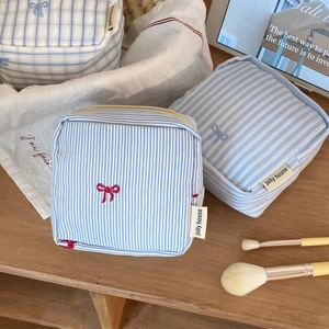 Three-piece set of cotton striped makeup pouches with delicate bow embroidery detail