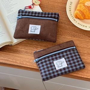 Close-up of suede patchwork card wallets with blue zippers and apple charms on a table