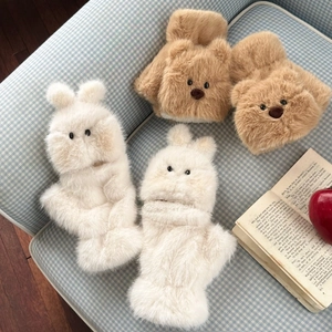 Close-up of soft plush bear and bunny flap gloves on a cozy plaid fabric background