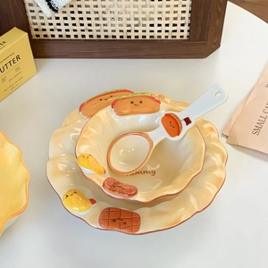 Macro detail of wave-edged ceramic bread plate and bowl set with embossed cartoon designs