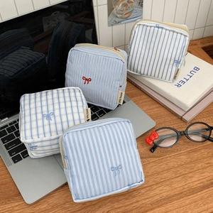 Close-up of small striped and checkered cotton pouches with bow embroidery and zipper
