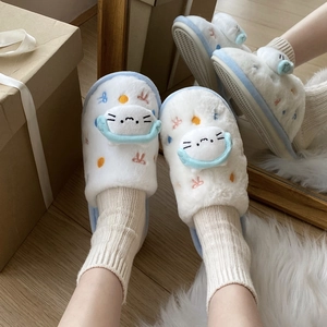 Détail des chaussons chat en peluche avec oreilles 3D et broderies sur fourrure blanche