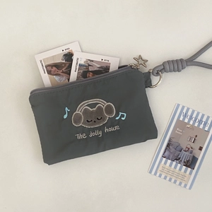Detailed embroidery of cat with headphones on a gray pouch with star pendant