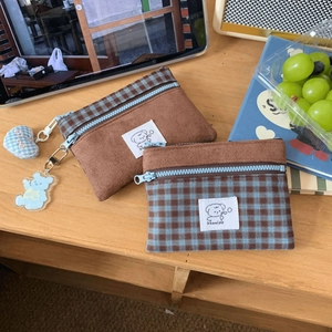 Detail of suede plaid card holder with cute bear pendant and puppy patch on wood table