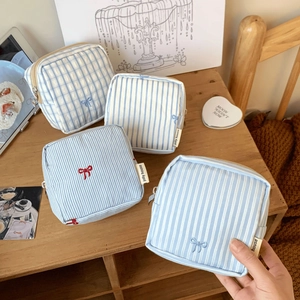 Detail of four blue and white striped fabric pouches with embroidered bows on a desk
