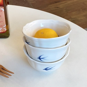 Dettaglio di tre ciotole in ceramica impilate con motivi di uccelli blu e bordi ondulati